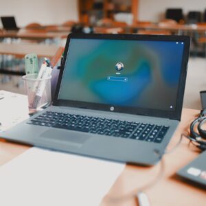 A close-up of a laptop on a desk in a classroom setting, ready for educational use.
