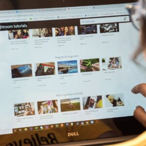 A woman exploring Adobe Lightroom tutorials online for learning and photo editing.